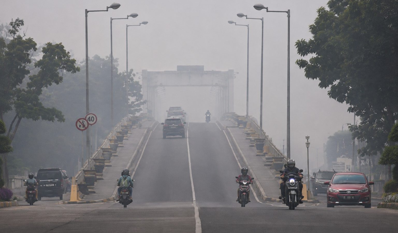 Warga melintas di sekitar Jembatan Kahayan, Palangka Raya yang terdampak kabut asap karhutla saat kualitas udara berada pada kategori berbahaya.