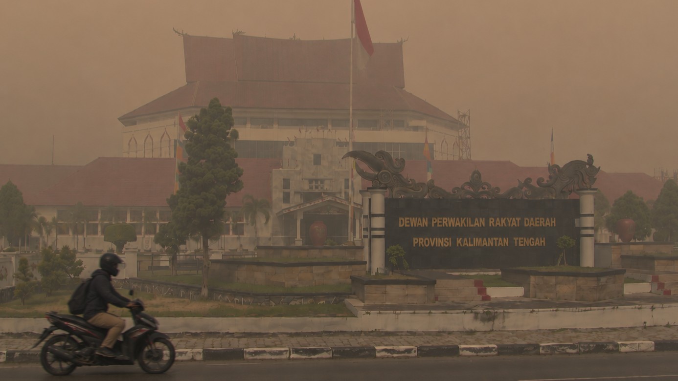Pengendara melintas di depan Gedung DPRD Kalimantan Tengah saat kepungan kabut asap pekat akibat karhutla.