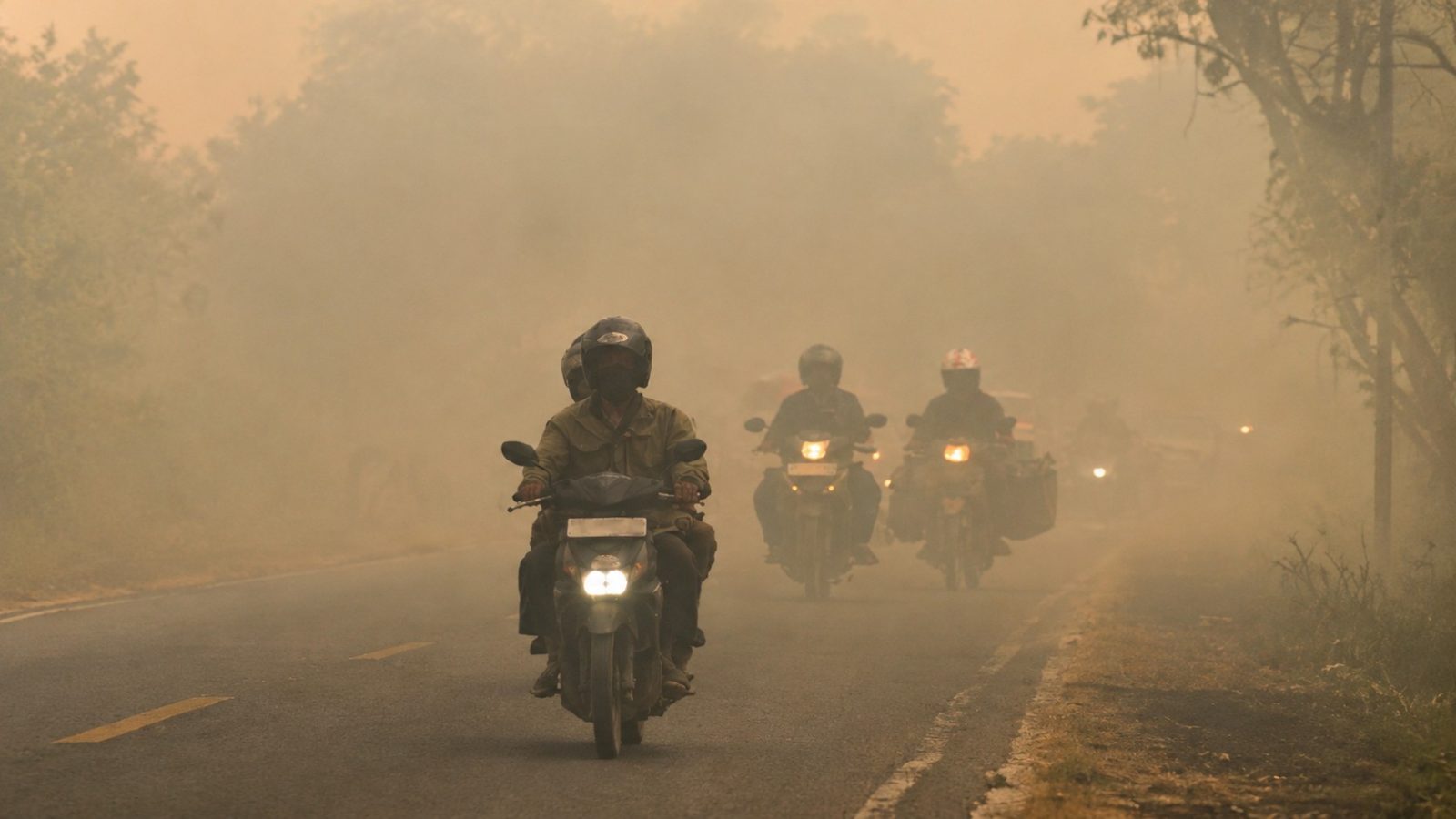 Sejumlah pengendara sepeda motor melintasi Jalan Tjilik Riwut, ruas Palangka Raya–Kasongan, di tengah kabut asap tebal yang membatasi jarak pandang.